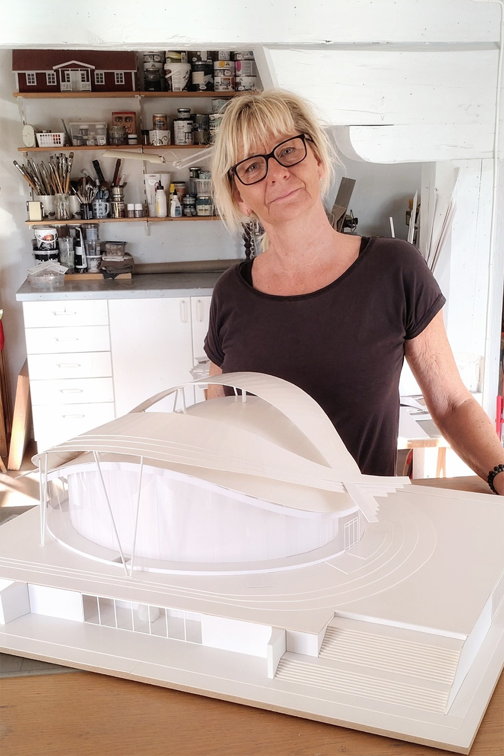 Kajsa i verkstad med stor modell av modernt hus